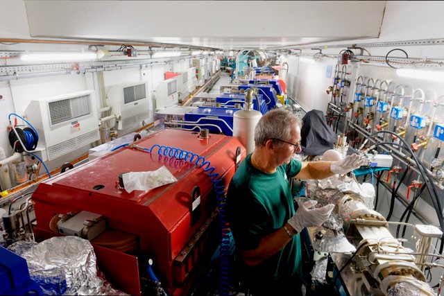 Intérieur de l'Anneau de stockage du Synchrotron Soleil. Cela ressemble à un long couloirs, légèrement arrondi, dont un couloir diverge.  Il est rempli d'éléments magnétiques rouges et bleus.