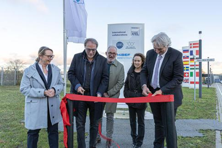 En signe visible de la création de l'IRL entre le CNRS et European XFEL, Sylvain Ravy, directeur adjoint scientifique à CNRS Physique (deuxième à partir de la gauche), et Thomas Feurer (à droite), Directeur Général d’European XFEL, ont coupé le ruban rouge devant la stèle sur laquelle figure le logo du CNRS. 