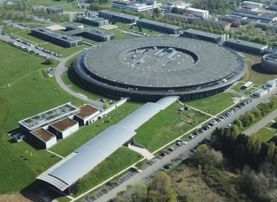 Vue aérienne du synchrotron Soleil. Au fond un grand bâtiment circulaire. Deux bâtiments allongés en sortent