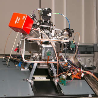 Sur chacun des trois axes de mesure un accéléromètre mécanique est fixé sur le miroir de référence de l’interféromètre atomique, formant l’hybridation classique/quantique permettant une mesure continue sans biais de l’accélération. Les trois composantes permettent de mesurer le vecteur `accélération` suivant une direction arbitraire. Le capteur est fixé sur une plateforme de rotation permettant la démonstration de la mesure pour différents angles.