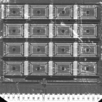Photographie de la machine Bayésienne (dimension 2mmx2mm). Les seize blocs de memristors (apparaissant comme des carrés noirs) sont entourés de circuits à base de transistors.