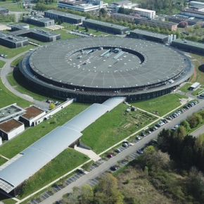 Vue aérienne du synchrotron Soleil. Au fond un grand bâtiment circulaire. Deux bâtiments allongés en sortent